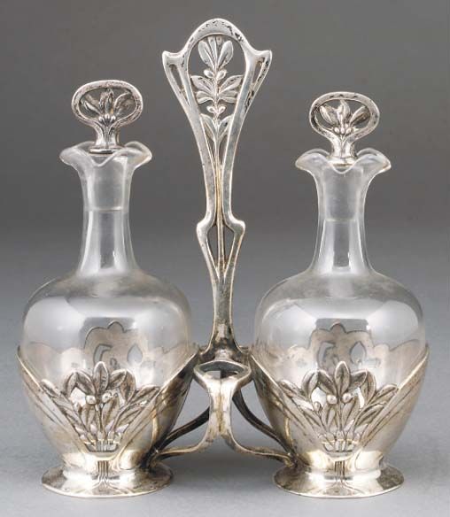 A SILVERED METAL AND GLASS OIL AND VINEGAR SET - DESIGNED BY FELIX .