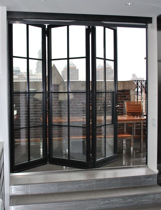 a large black framed folding door is an entrance to the balcony .