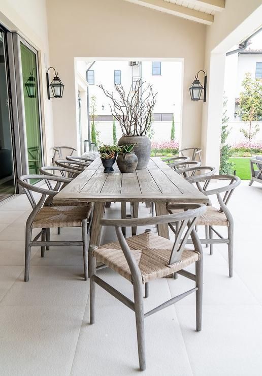 This beautiful covered patio dining space features gray wishbone .