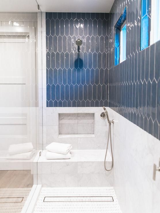 Frameless glass walk-in shower boasts slate blue picket surround .