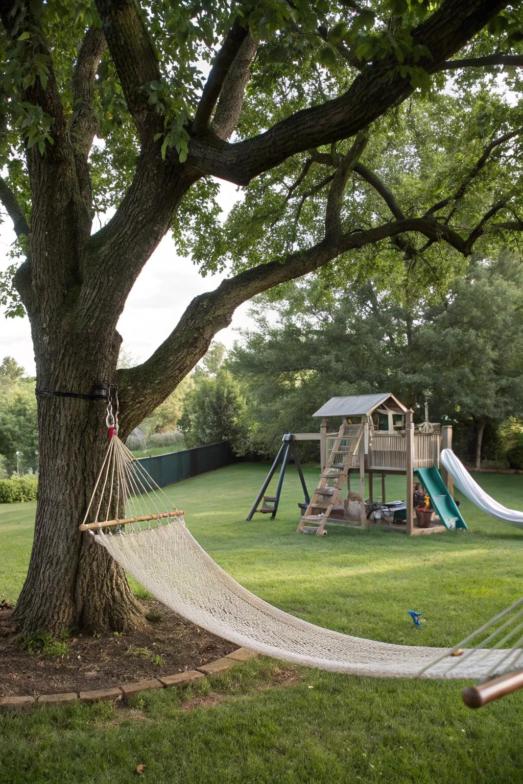 A backyard with a hammock under a tree and play area.