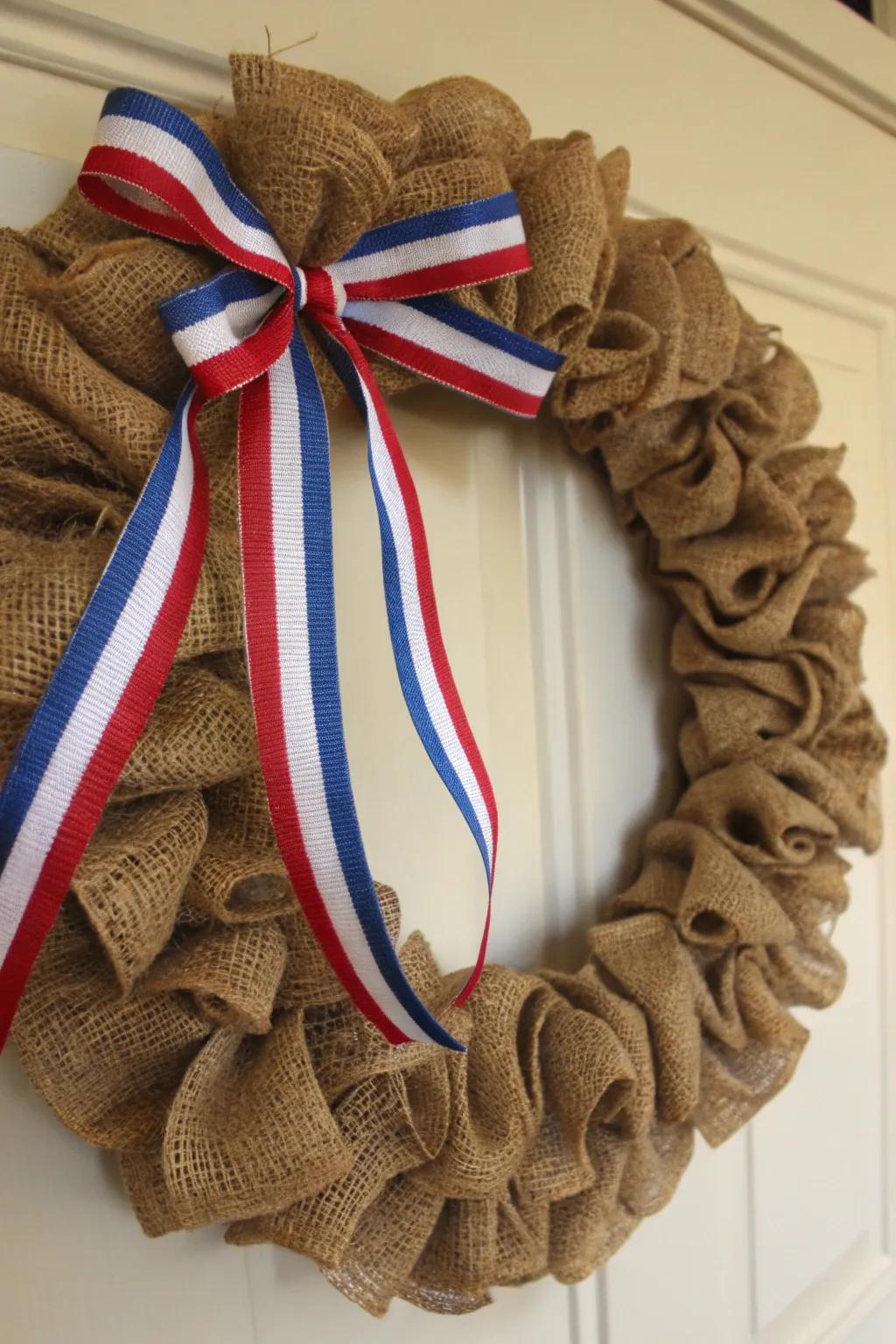 A rustic burlap wreath adorned with vibrant patriotic ribbons.