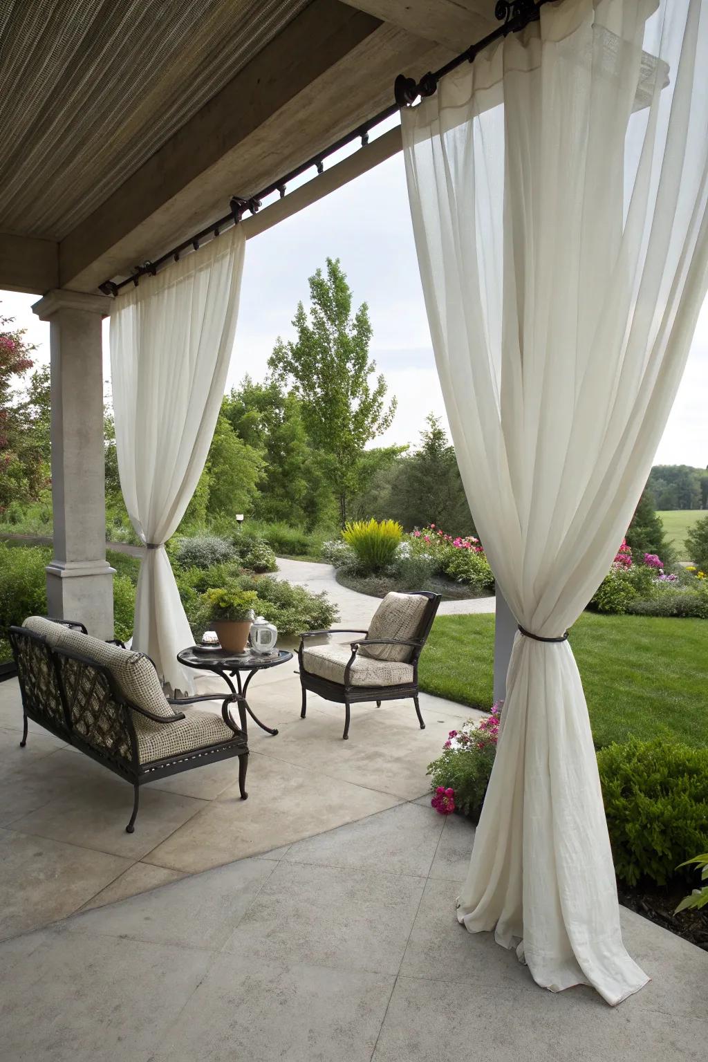 A concrete patio with elegant outdoor curtains providing privacy and shade.