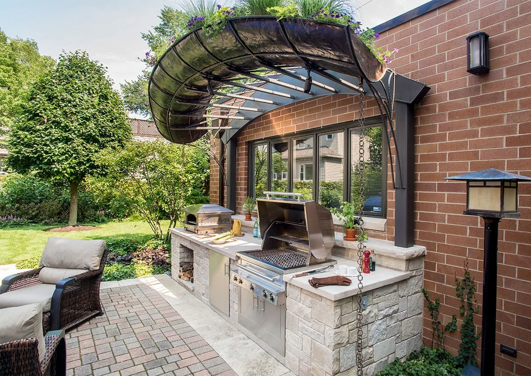 7. Curved Metal Awning Kitchen in Warm Stone & Stainless Steel (Small Outdoor Kitchen Ideas)