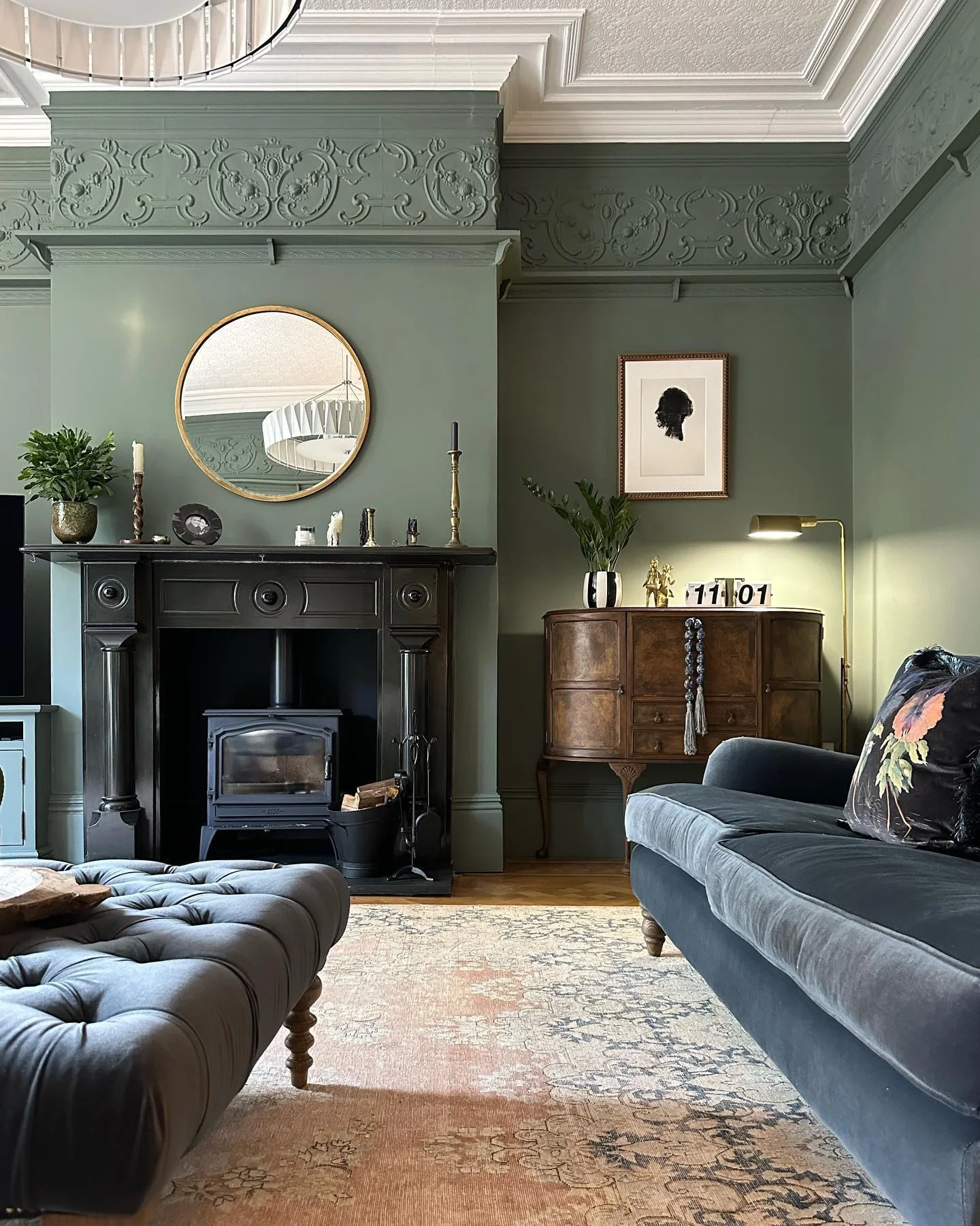 2. Dark Blue Sofa with Sage Green Walls & Classic Black Fireplace (Dark Sofa Living Room Ideas)