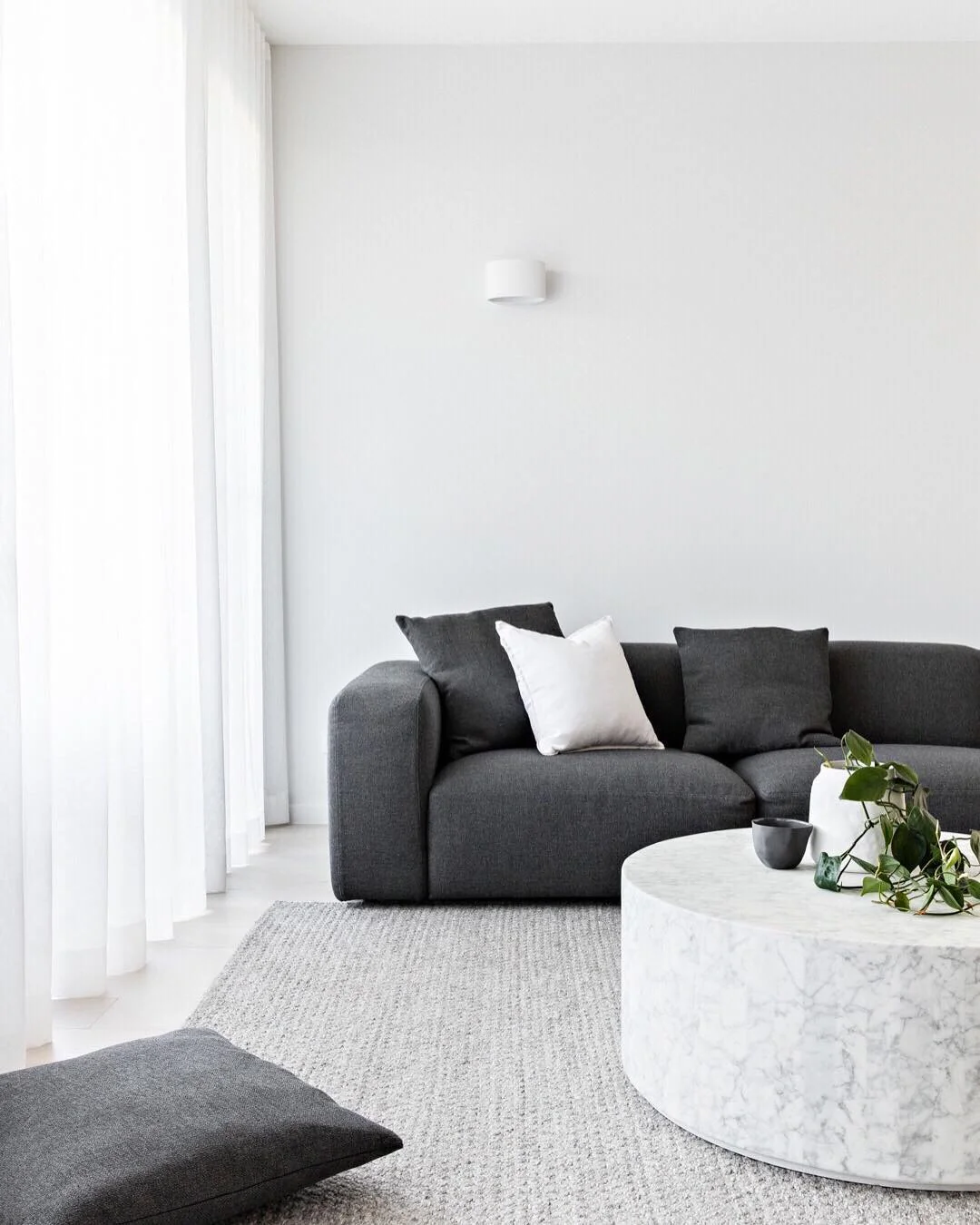 3. Charcoal Sofa in an All-White Minimalist Living Room (Dark Sofa Living Room Ideas)