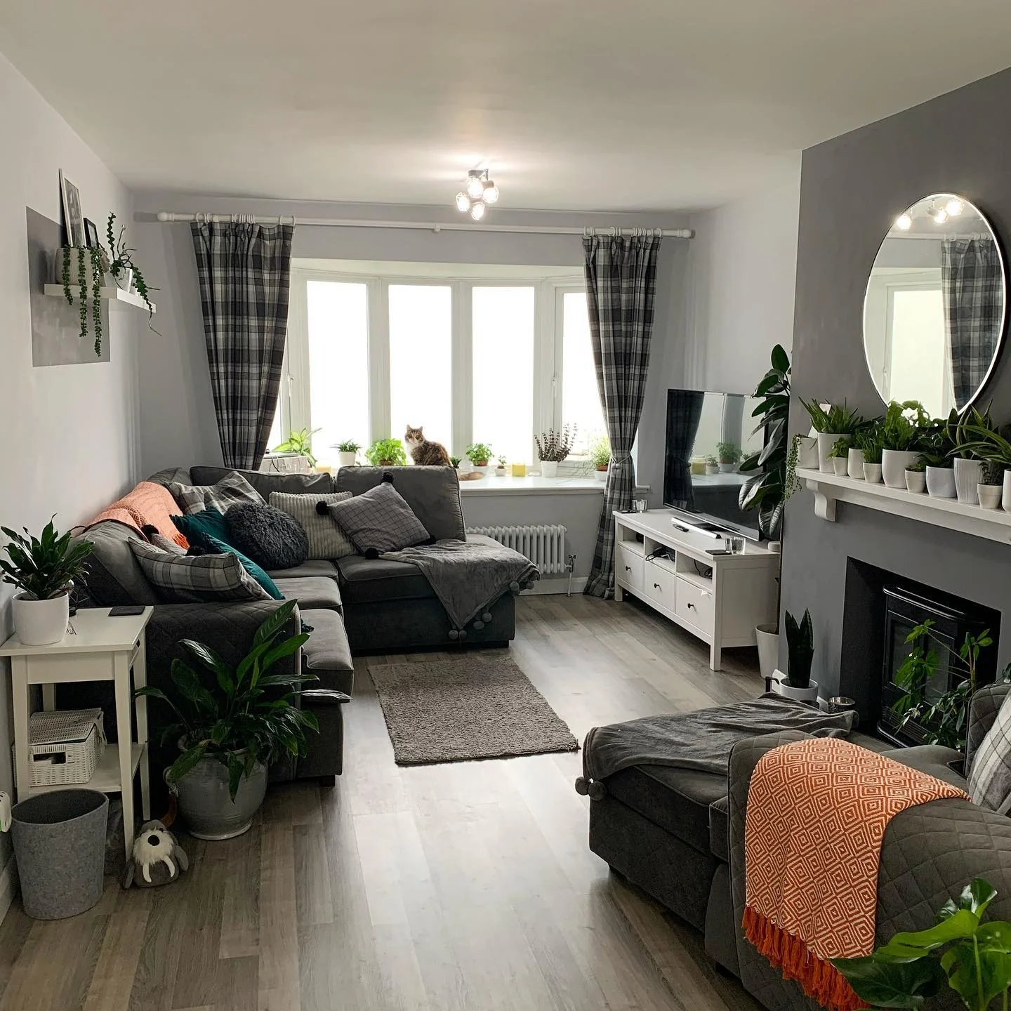 4. Grey Sectional Living Room with Soft Orange & Green Styling (Dark Sofa Living Room Ideas)