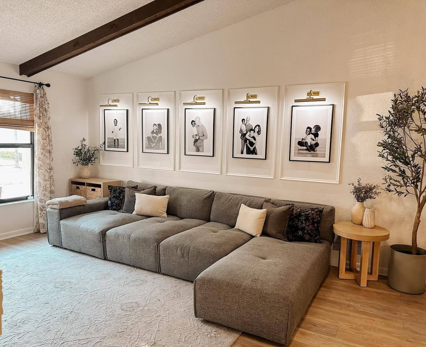 13. Gallery Wall with Family Portraits and Warm Lighting (Large Living Room Wall Ideas)