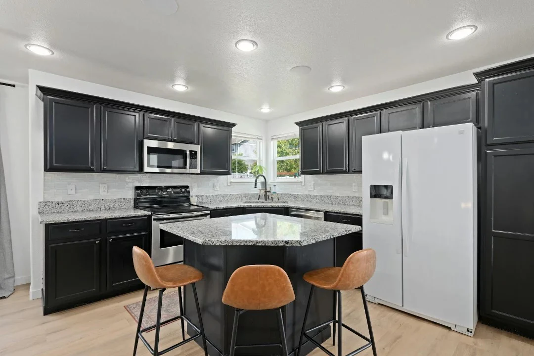 4. Classic Meets Contrast with Granite Detail (Black Cabinets Kitchen Ideas)